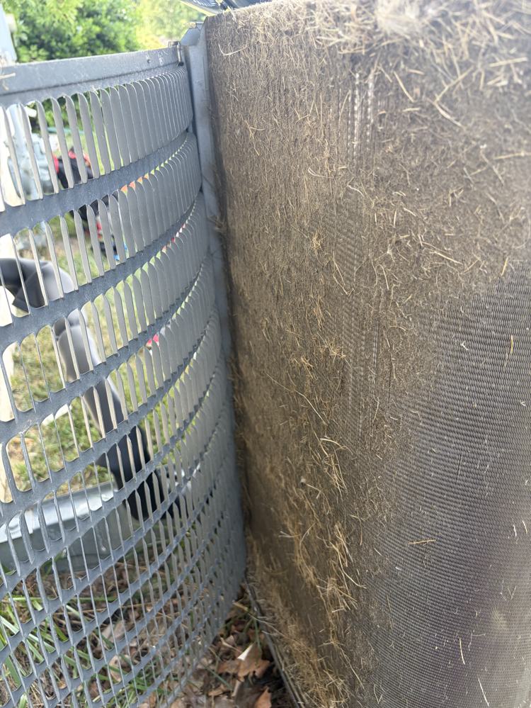 Condenser coil matted with grass and debris before cleaning